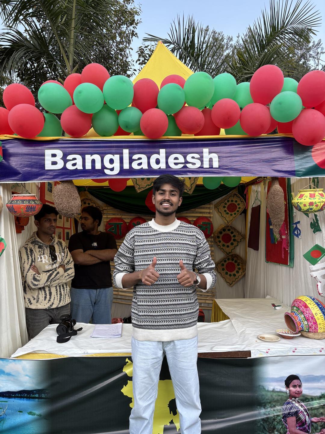 লাল-সবুজ বেলুনে সাজানো Bangladesh স্টলের সামনে মৃণাল দাস