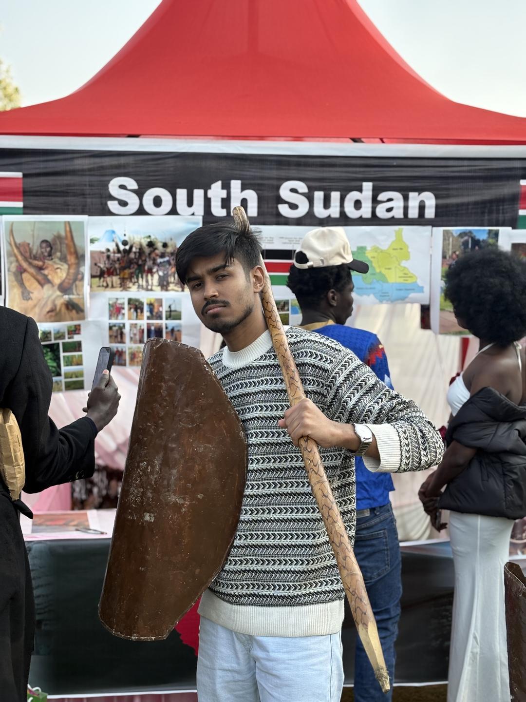 Global Village-এ South Sudan-এর স্টলে ঢাল আর লাঠি হাতে মৃণাল দাস