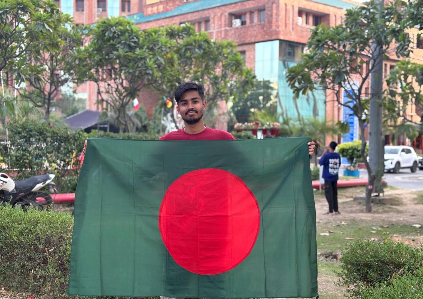 ক্যাম্পাসের ভবনের সামনে বাংলাদেশের পতাকা হাতে মৃণাল দাস